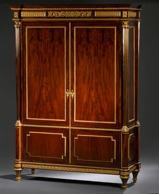 une armoire ancienne en bois à deux portes, ornée de garnitures dorées