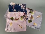 trois serviettes de table ornées de fleurs et de feuilles, posées sur une table