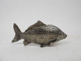 a silver fish figurine on a white surface