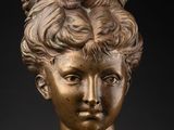 a bronze bust of a woman with a braided hair