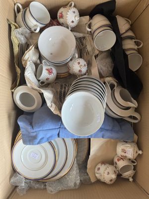une boîte en carton remplie d'une multitude d'assiettes et de tasses
