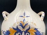 un vase blanc orné d'un motif bleu et jaune