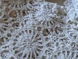 a white crocheted sweater laying on top of a bed