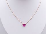 a necklace with a heart shaped pink stone hangs on a mannequin