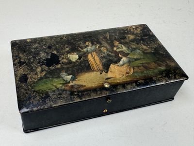 une boîte noire ornée d'une peinture, posée sur une table