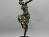 statue en bronze représentant une femme vêtue d'une robe verte, posée sur un socle noir