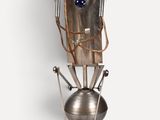 une sculpture représentant un robot, posée sur un socle en bois