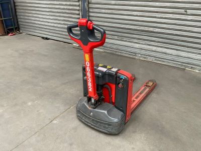a red and black forklift sitting in front of a garage door