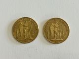 two gold coins sitting on top of each other on a white surface