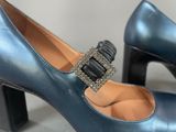 pair of women ' s blue shoes with a metal buckle on the heel