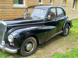 a old black car parked in front of a house