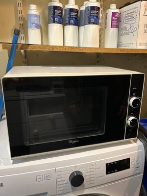 un micro-ondes posé sur une machine à laver et un sèche-linge