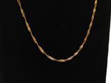 a gold necklace with a chain on a black mannequin