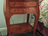 a small table with a lamp on top of it next to a bed