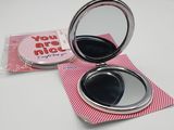 a compact mirror that is sitting on top of a piece of paper