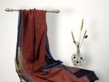 une serviette rouge et bleue posée sur un porte-serviettes à côté d'un vase de fleurs