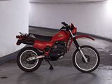 a red motorcycle parked in a parking garage next to a white wall