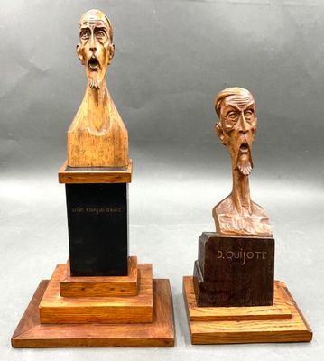 pair of wooden busts of two men with a plaque in the middle of them