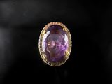 a close up of a ring with a purple stone in it