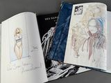 three books with drawings of women on them on a table