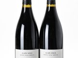 two bottles of red wine sitting next to each other on a white surface