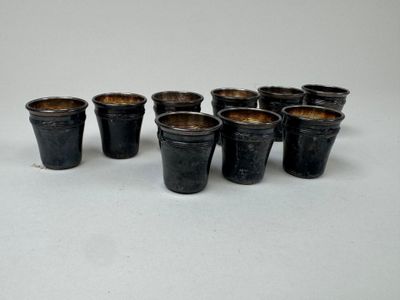 six petits pots noirs sont alignés sur une surface blanche