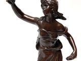 bronze statue of a woman holding an apple in one hand and a ball in the other