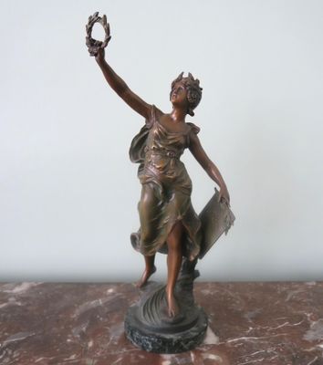 bronze statue of a woman holding a bird on a marble base