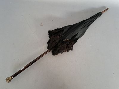 un parapluie noir posé par terre sur une surface blanche