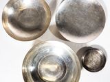trois bols en argent et un bol en argent posés sur une surface blanche