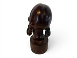 a small wooden sculpture of a woman with ear rings on it ' s head