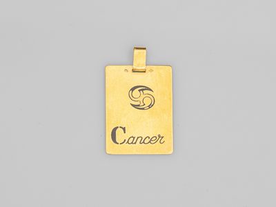 un pendentif plaqué or sur lequel est gravé le mot « cancer »
