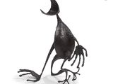 a metal sculpture of a bird that is sitting on the ground