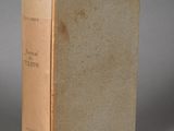 an old book sitting on top of a table next to a cup
