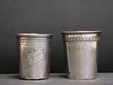 deux tasses en argent posées l'une à côté de l'autre sur une table