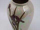 a white vase with purple flowers on it on a white surface