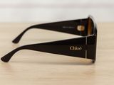 black sunglasses with gold logo on the side of them on a wooden table