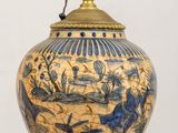 a blue and gold vase on a table with a lamp on it