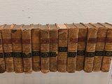 Plusieurs livres anciens sont empilés les uns sur les autres dans une vitrine.