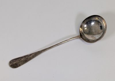 une cuillère en argent avec un manche de cuillère sur une surface blanche