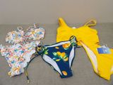 several swimsuits are laid out on a couch with a price tag