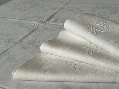 three folded napkins sitting on a table with a monogramed design