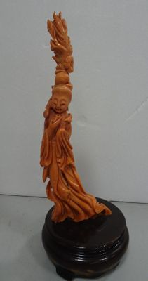 carved figurine of a woman holding a bird on a wooden base