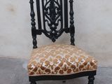 une chaise dont l'assise est à motif léopard et dont le piètement est noir