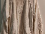 the sweater is hanging on a hanger in the corner of a room