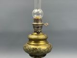 une lampe à huile ancienne en laiton, surmontée d'un globe en verre transparent