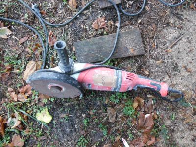 un sèche-cheveux rouge et noir posé par terre à côté d'un morceau de bois