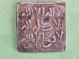 an old silver coin with writing on it sitting on a green surface