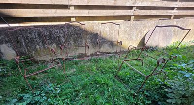 une chaise en métal rouillée posée dans l'herbe près d'un mur