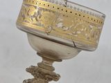 silver and gold plated chalicet on a stand with a hand holding it